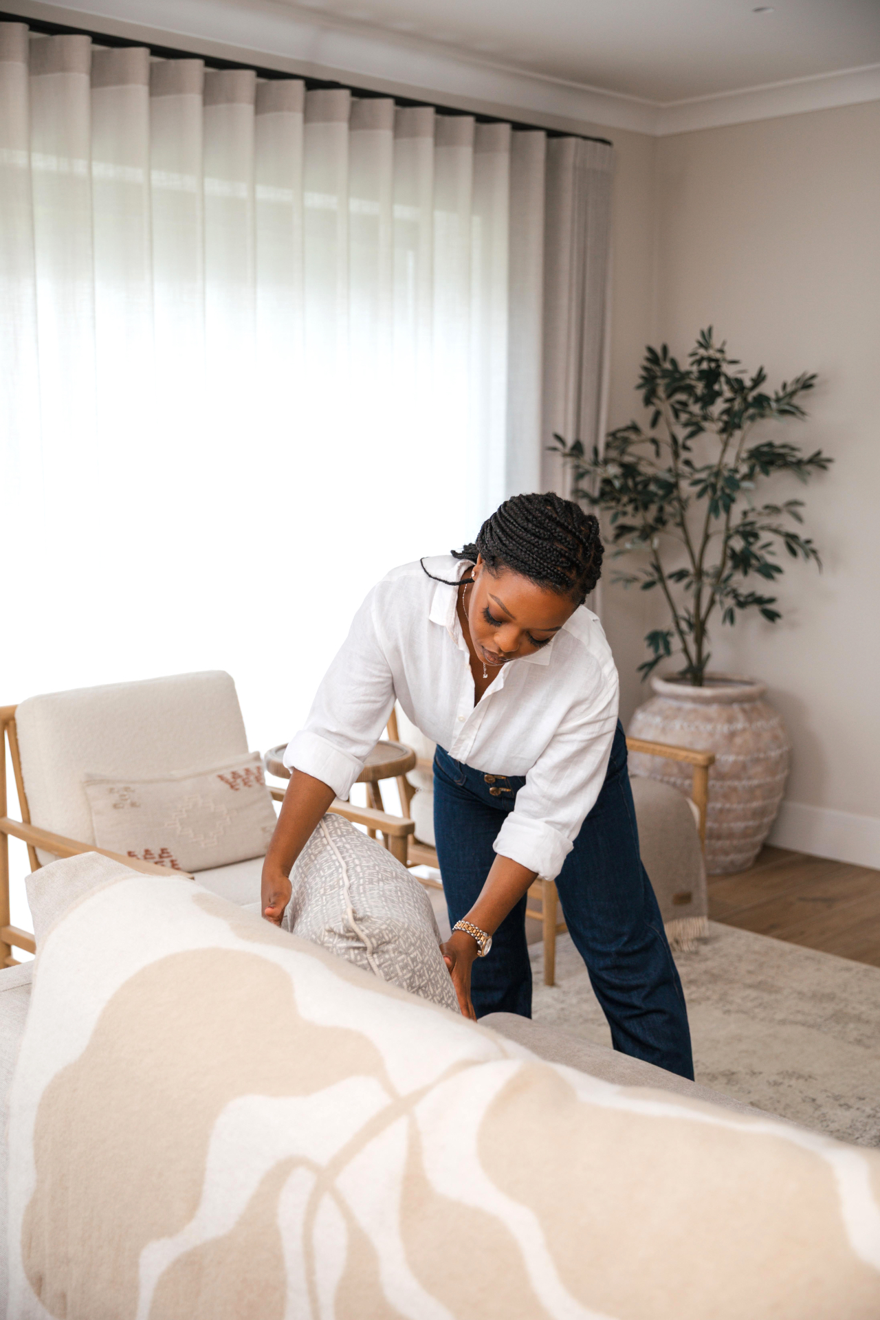 Shuvi arranging cushions in a light, styled living room